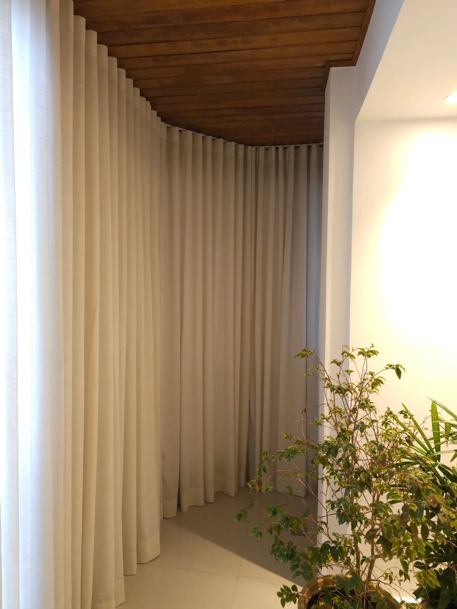 Cortina Wave em linho natural em trilho curvo de varanda com teto de madeira