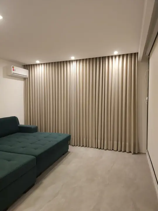 Cortina blackout bege em sala de TV com sofá verde