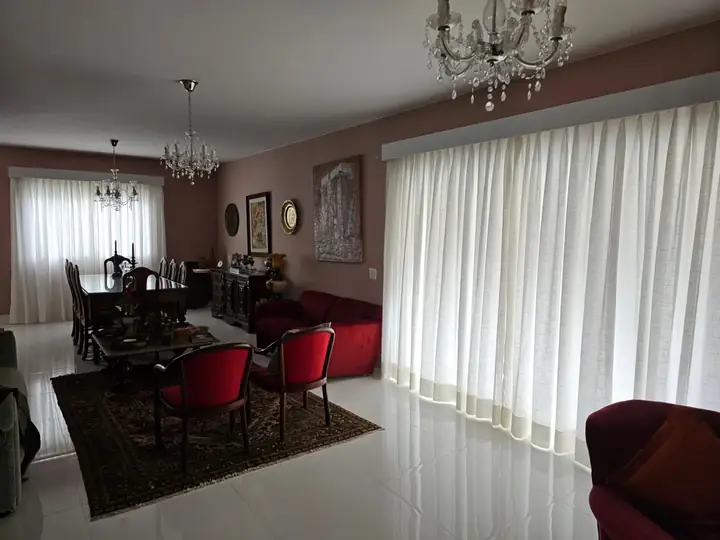 Cortinas de linho claro em sala de jantar clássica com lustres de cristal