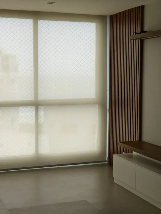 Detalhe de persiana rolô com tela padrão diamante em ambiente com marcenaria ripada